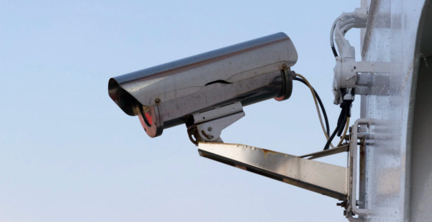 A surveillance camera on a wall outside a commercial facility