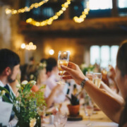 Several people raise their glasses for a toast on a long dinner table