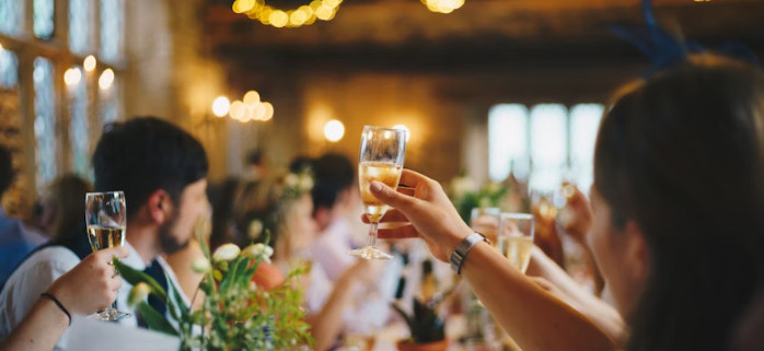 Several people raise their glasses for a toast on a long dinner table
