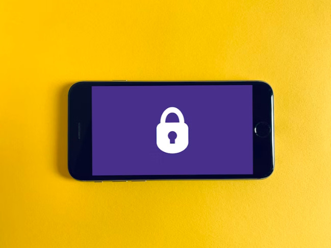A smartphone displaying a lock on a screen placed against a yellow background